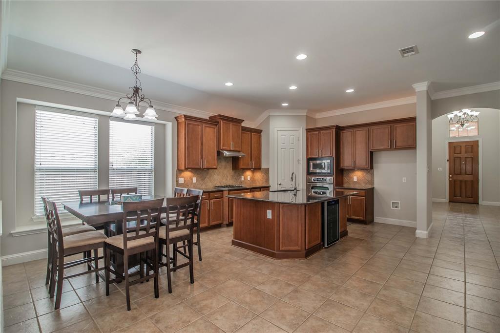 4647 Phillip Drive Plano, TX 75024 - Photo 9 of 38 a kitchen with stainless steel appliances granite countertop a stove top oven a sink dishwasher a dining table and chairs with wooden floor