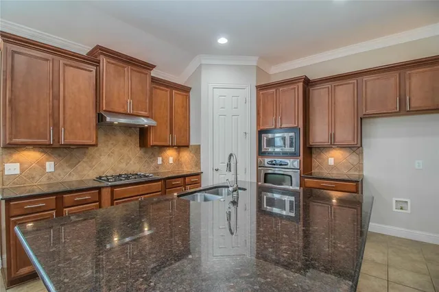 a kitchen with stainless steel appliances granite countertop a refrigerator a stove and a sink with wooden cabinets