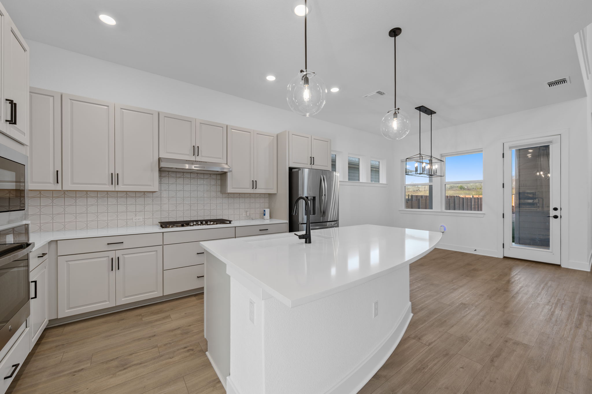 5902 Rangeland Road Austin, TX 78747 - Photo 11 of 35 Kitchen with an island with sink, decorative light fixtures, light wood-type flooring, recessed lighting, and decorative backsplash