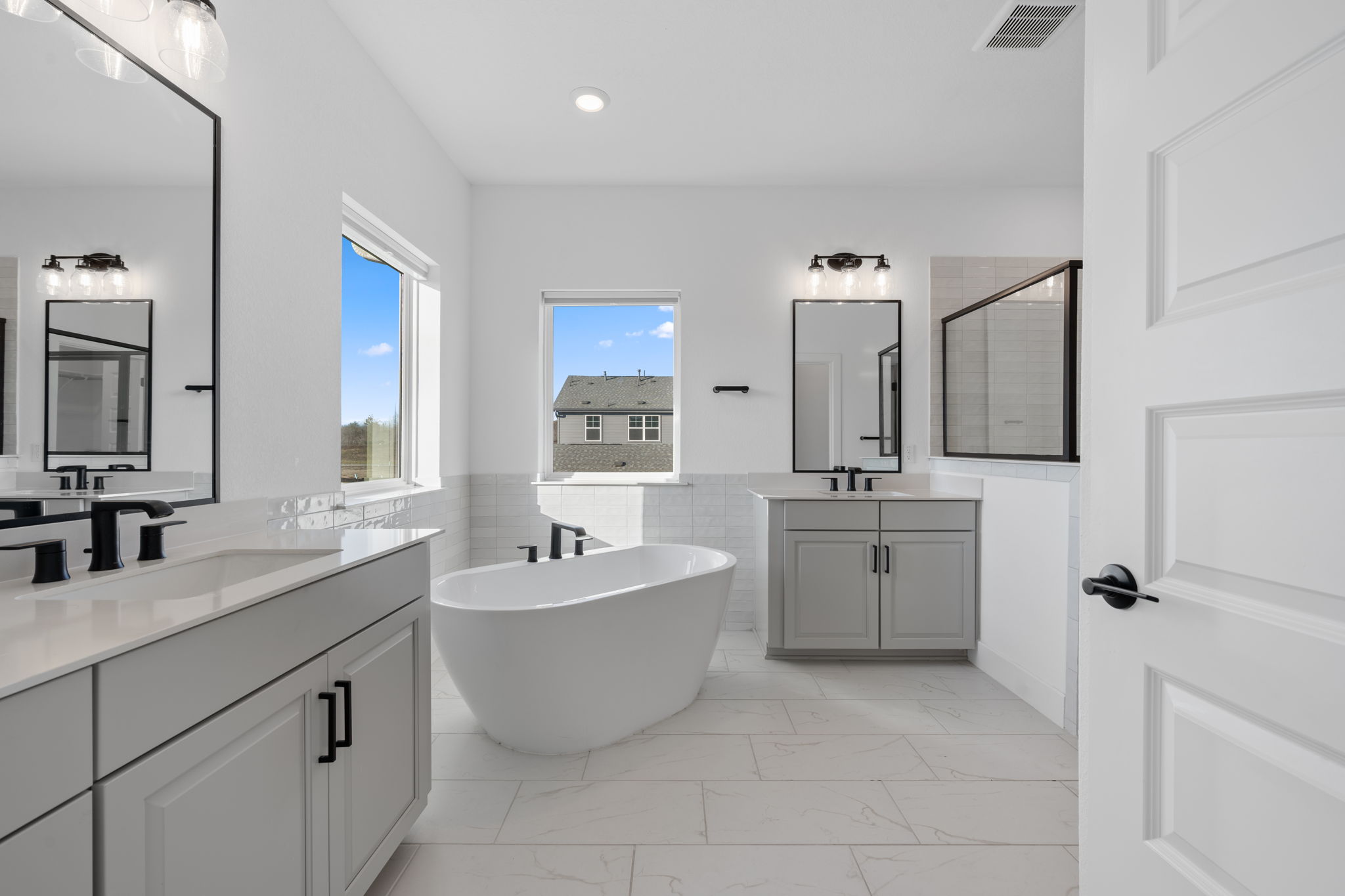 5902 Rangeland Road Austin, TX 78747 - Photo 21 of 35 Bathroom with a freestanding tub, a shower stall, two vanities, tile walls, and light marble finish floors