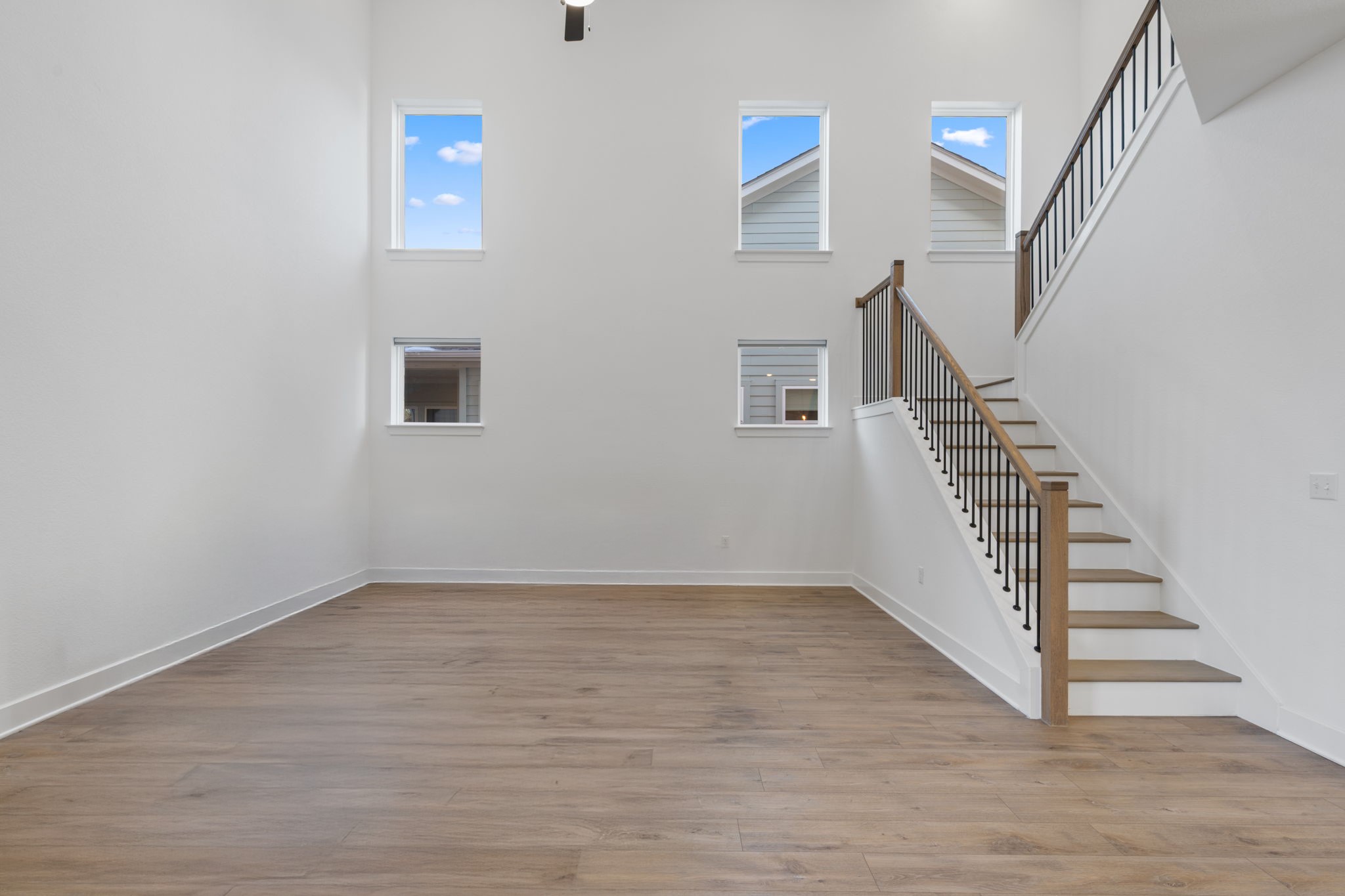 5902 Rangeland Road Austin, TX 78747 - Photo 7 of 35 Unfurnished living room with a towering ceiling, light wood-style flooring, stairs, and plenty of natural light