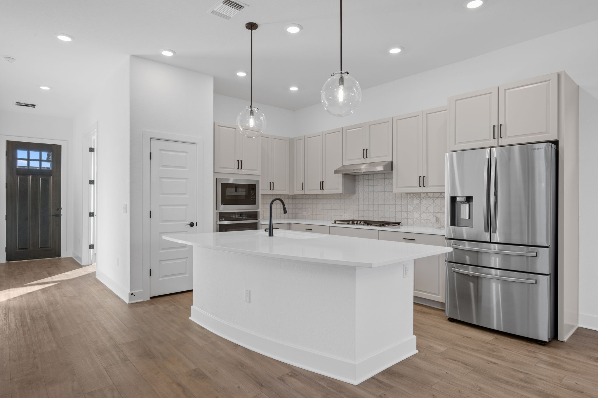 5902 Rangeland Road Austin, TX 78747 - Photo 9 of 35 Kitchen with appliances with stainless steel finishes, a center island with sink, decorative light fixtures, light wood-style flooring, and recessed lighting