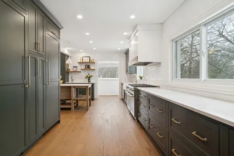 a kitchen with stainless steel appliances kitchen island granite countertop a sink counter space cabinets and a large window
