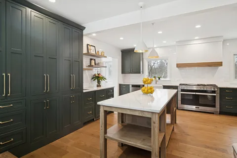 a kitchen with stainless steel appliances kitchen island granite countertop a table chairs and a refrigerator