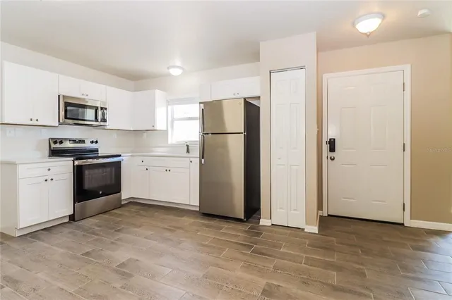 a kitchen with stainless steel appliances a refrigerator sink and white cabinets