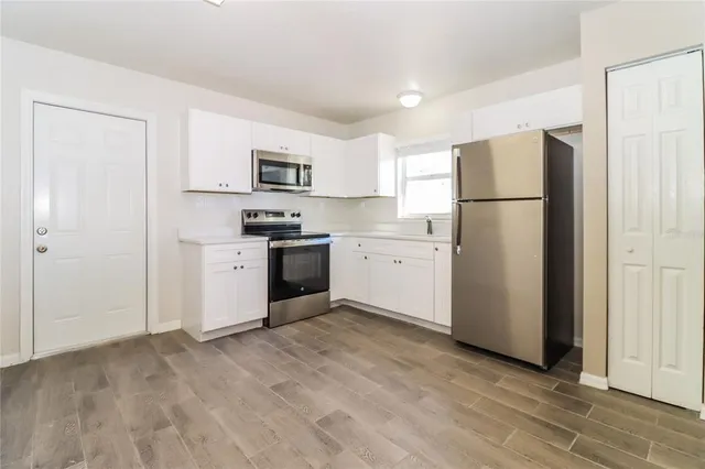 a kitchen with a refrigerator a stove top oven and white cabinets