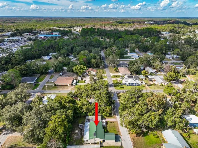 an aerial view of residential houses with outdoor space and trees