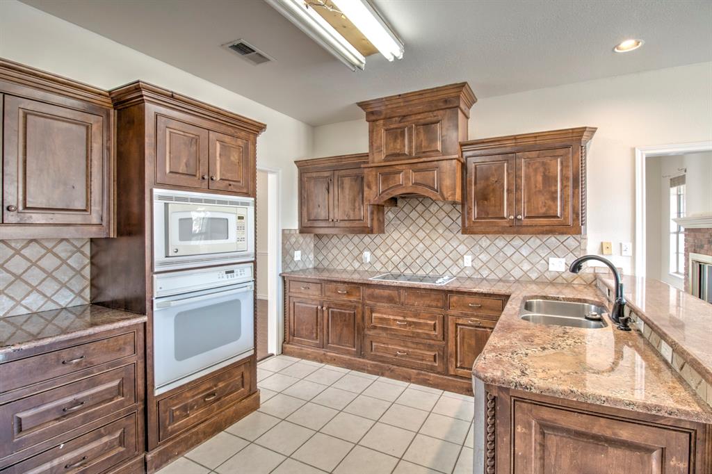 1400 North St Charles Street Pilot Point, TX 76258 - Photo 12 of 30 a kitchen with granite countertop cabinets and steel stainless steel appliances