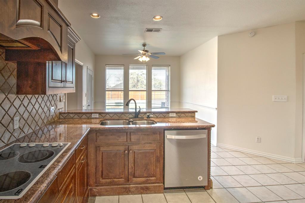 1400 North St Charles Street Pilot Point, TX 76258 - Photo 13 of 30 a kitchen with stainless steel appliances granite countertop a sink stove and cabinets