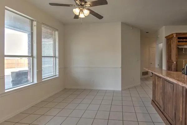 a view of an empty room with window and chandelier fan