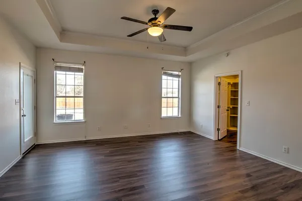 a view of empty room with wooden floor and fan