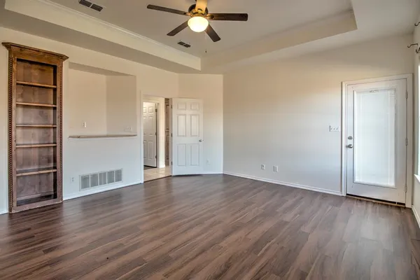 an empty room with wooden floor chandelier fan and windows