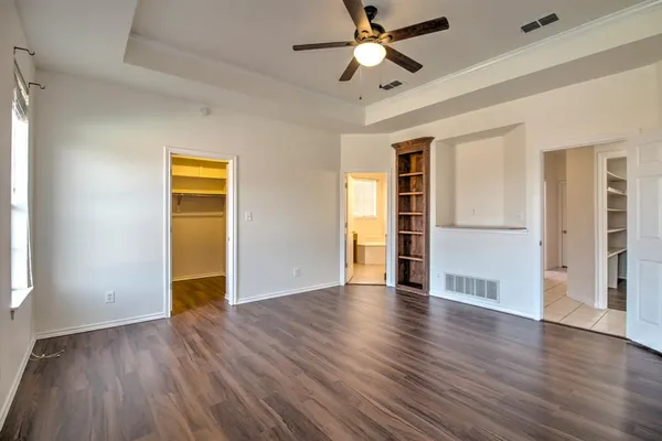 an empty room with wooden floor closet and windows