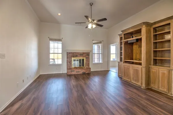 an empty room with wooden floor fireplace and windows