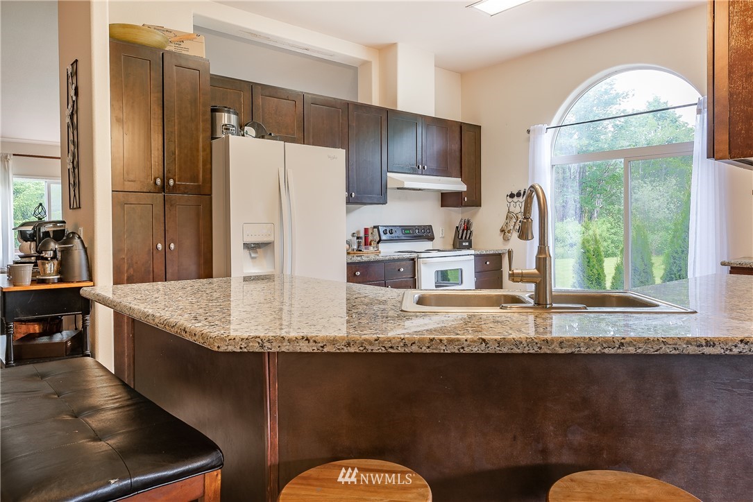 4165 Deming Road Everson, WA 98247 - Photo 10 of 31 a kitchen with kitchen island granite countertop a refrigerator a stove a sink and a dining table with wooden cabinet