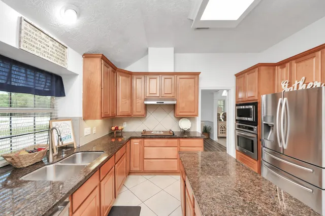 a kitchen with stainless steel appliances granite countertop sink stove top oven and cabinets