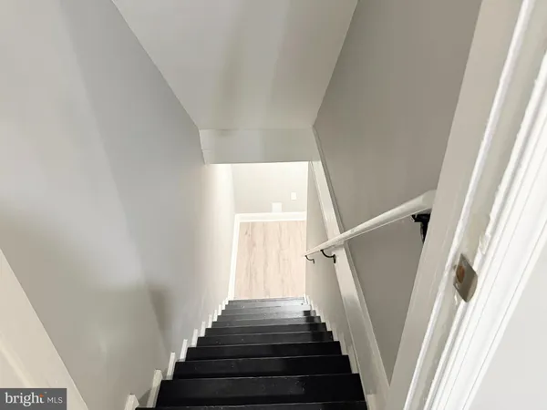 a view of staircase with wooden floor and white walls