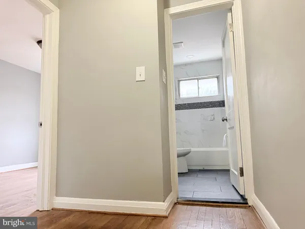 a view of a hallway with wooden floor and a bathroom