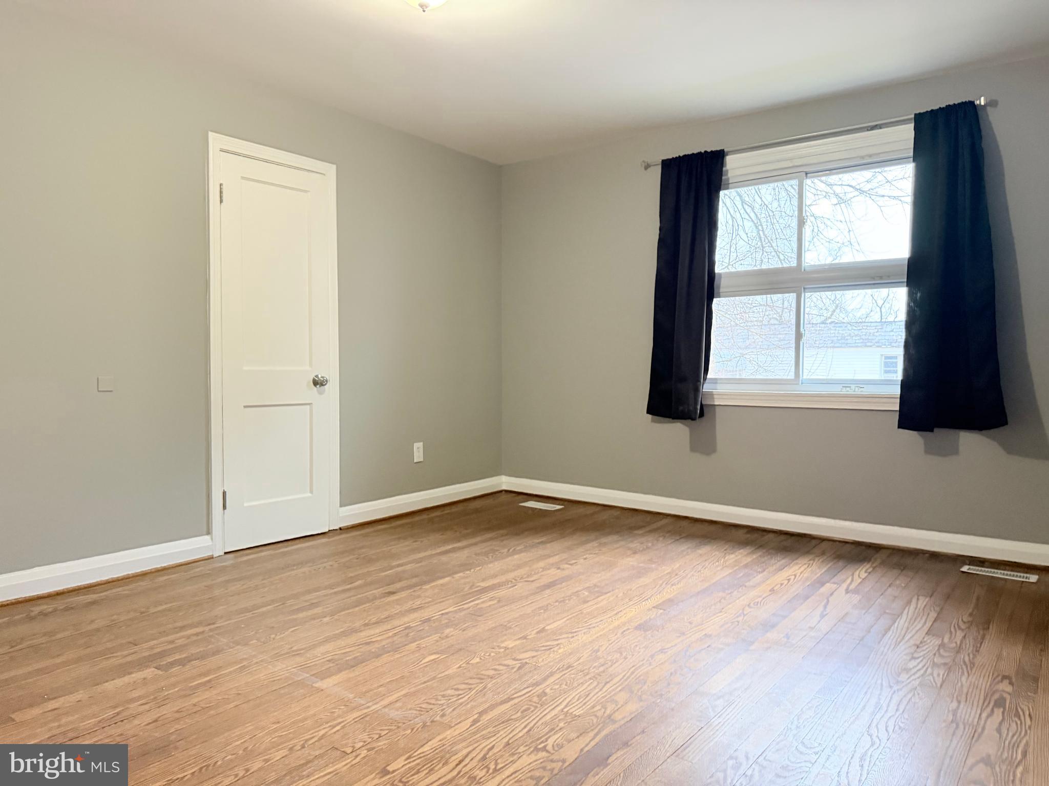 5115 Pembridge Avenue Baltimore, MD 21215 - Photo 28 of 29 an empty room with wooden floor and windows