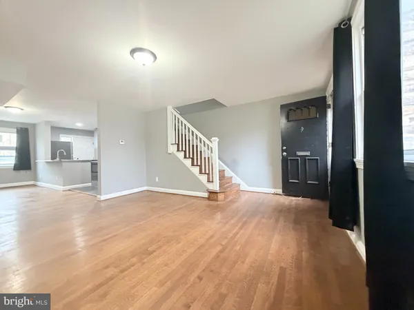 a view of a hallway with wooden floor and a kitchen