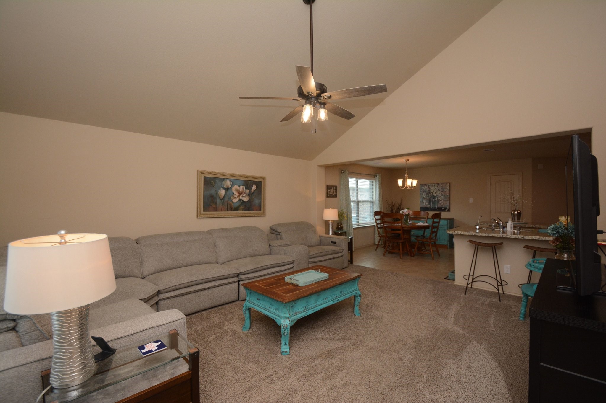 23318 Dukes Run Drive Spring, TX 77373 - Photo 14 of 41 This spacious living area features a high ceiling with a ceiling fan. The open layout seamlessly connects to the dining area and kitchen, creating an inviting space for entertaining. Neutral tones and soft carpeting add warmth and comfort.
