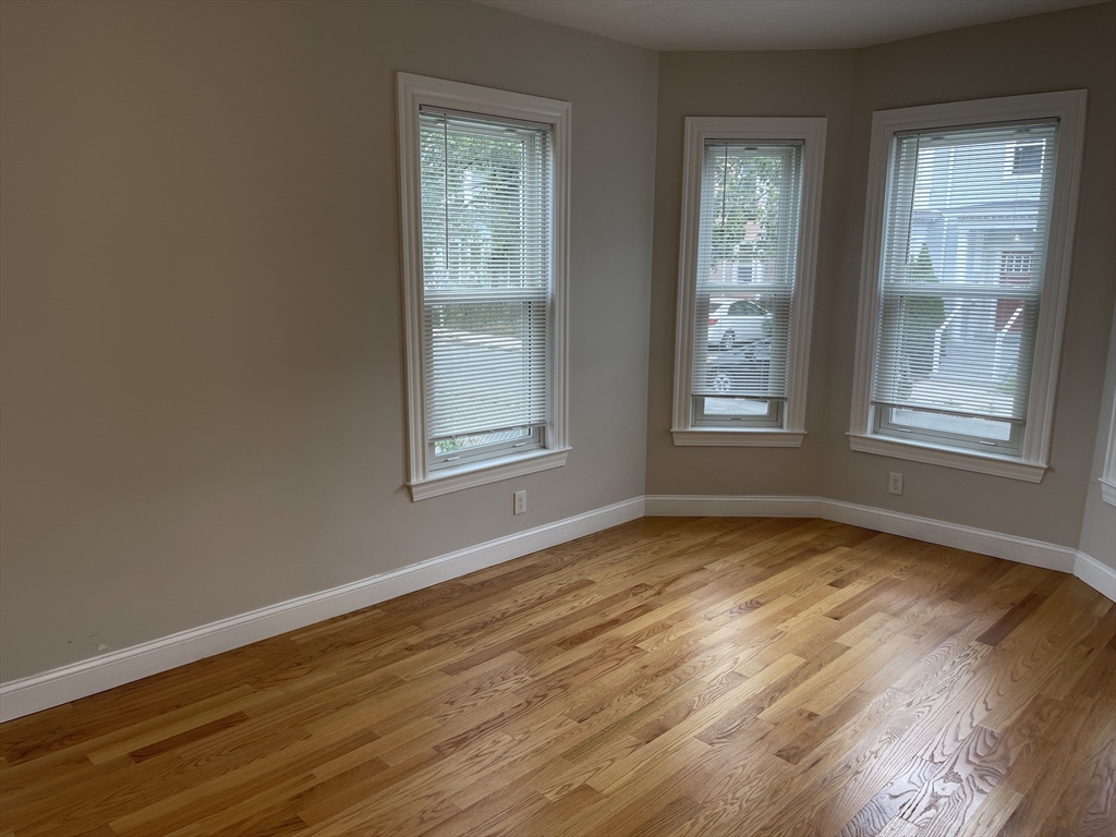 79 Newton Street, Unit 79 Somerville, MA 02143 - Photo 7 of 24 a view of an empty room with wooden floor and a window