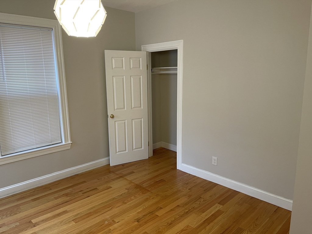 79 Newton Street, Unit 79 Somerville, MA 02143 - Photo 9 of 24 an empty room with wooden floor and windows