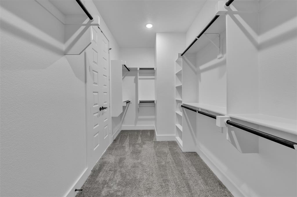 2004 Willy Dilly Road Springtown, TX 76082 - Photo 31 of 40 Spacious walk-in closet featuring white built-in shelving, hanging rods, and textured carpeting