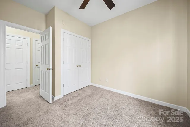 an empty room with closet and chandelier fan