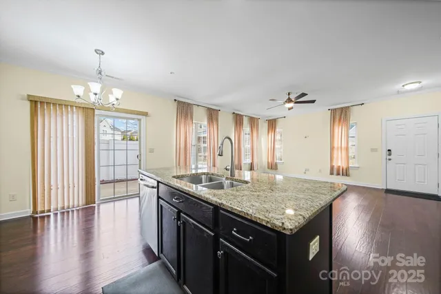 an empty room with kitchen island granite countertop wooden floor and a sink