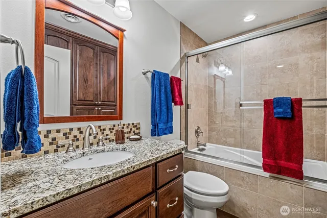 a bathroom with a granite countertop sink a toilet and shower