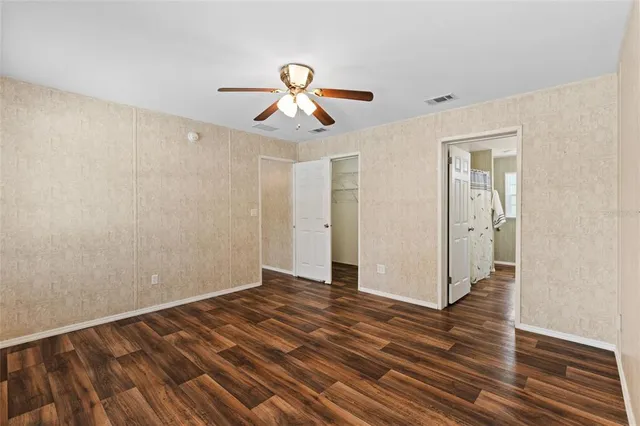 a view of a room with wooden floor and ceiling fan