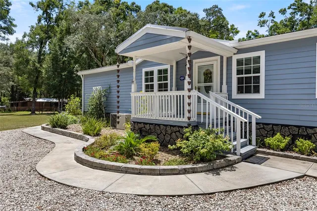 a front view of a house with a yard and potted plants