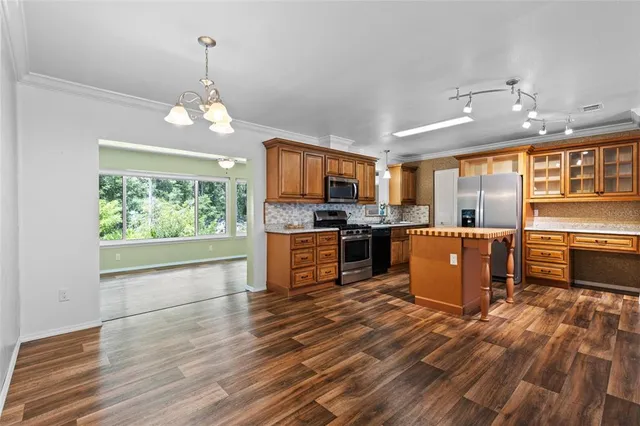 a large kitchen with granite countertop a large counter top stainless steel appliances and cabinets