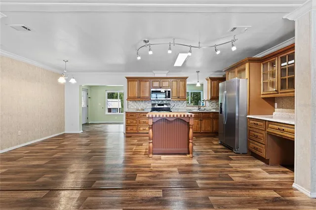 a kitchen with stainless steel appliances kitchen island granite countertop a refrigerator a stove top oven and a sink with granite countertops