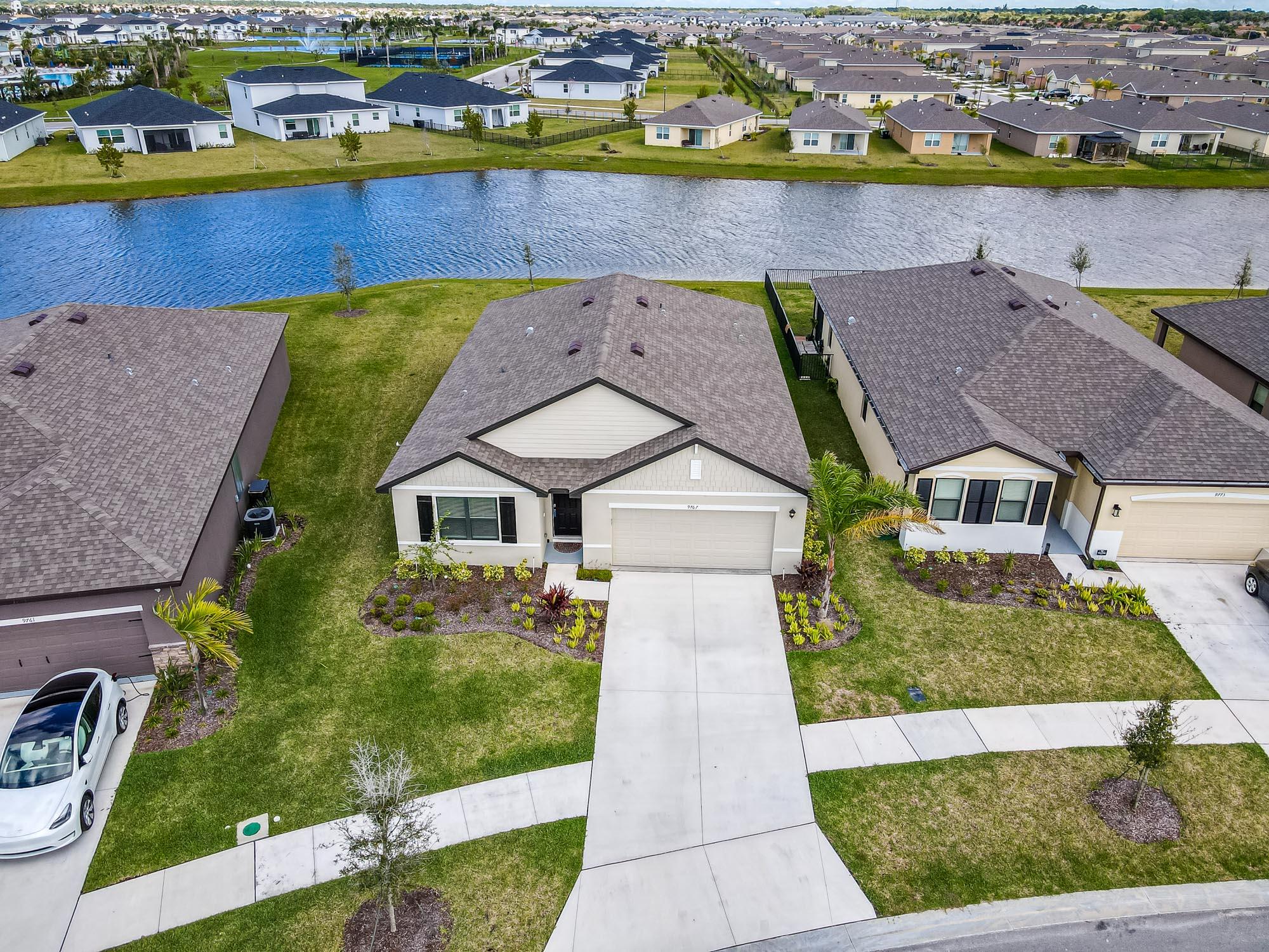 9767 Southwest Triton Way Port Port St. Lucie, FL 34987 - Photo 1 of 52 an aerial view of a house with a garden and lake view