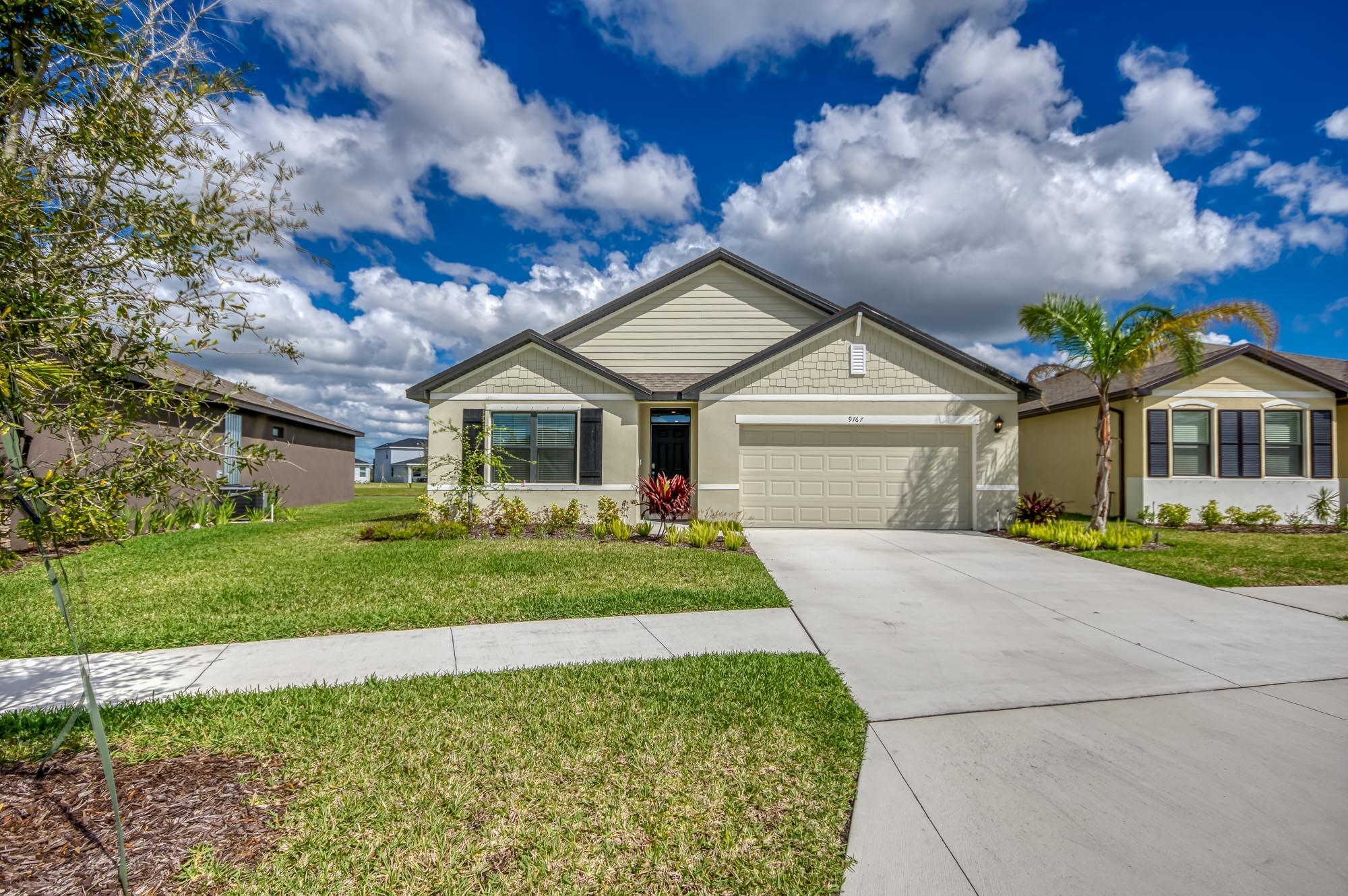 9767 Southwest Triton Way Port Port St. Lucie, FL 34987 - Photo 39 of 52 a front view of a house with a yard and garage