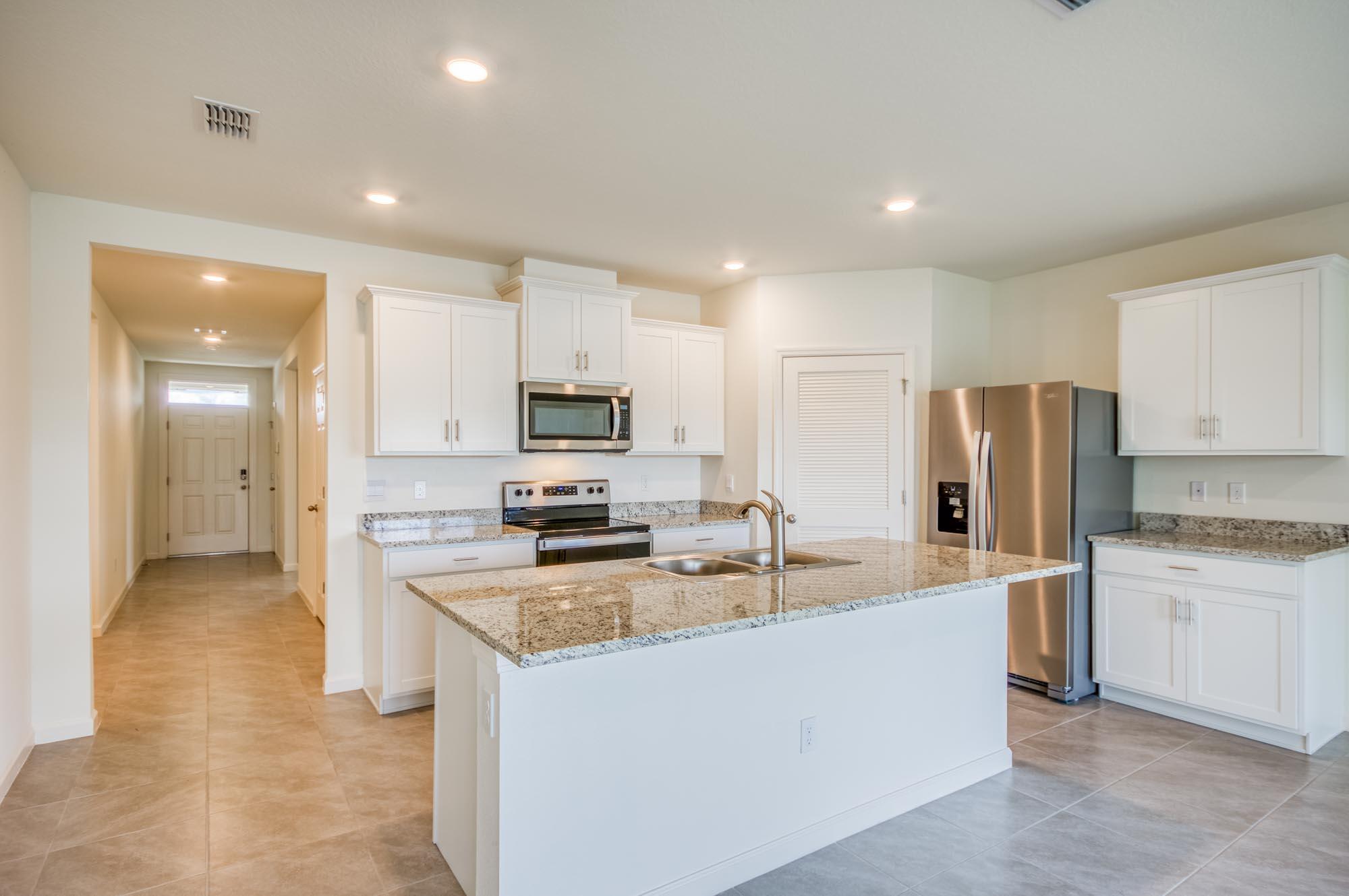 9767 Southwest Triton Way Port Port St. Lucie, FL 34987 - Photo 5 of 52 a kitchen with stainless steel appliances granite countertop a sink a stove a refrigerator and cabinets