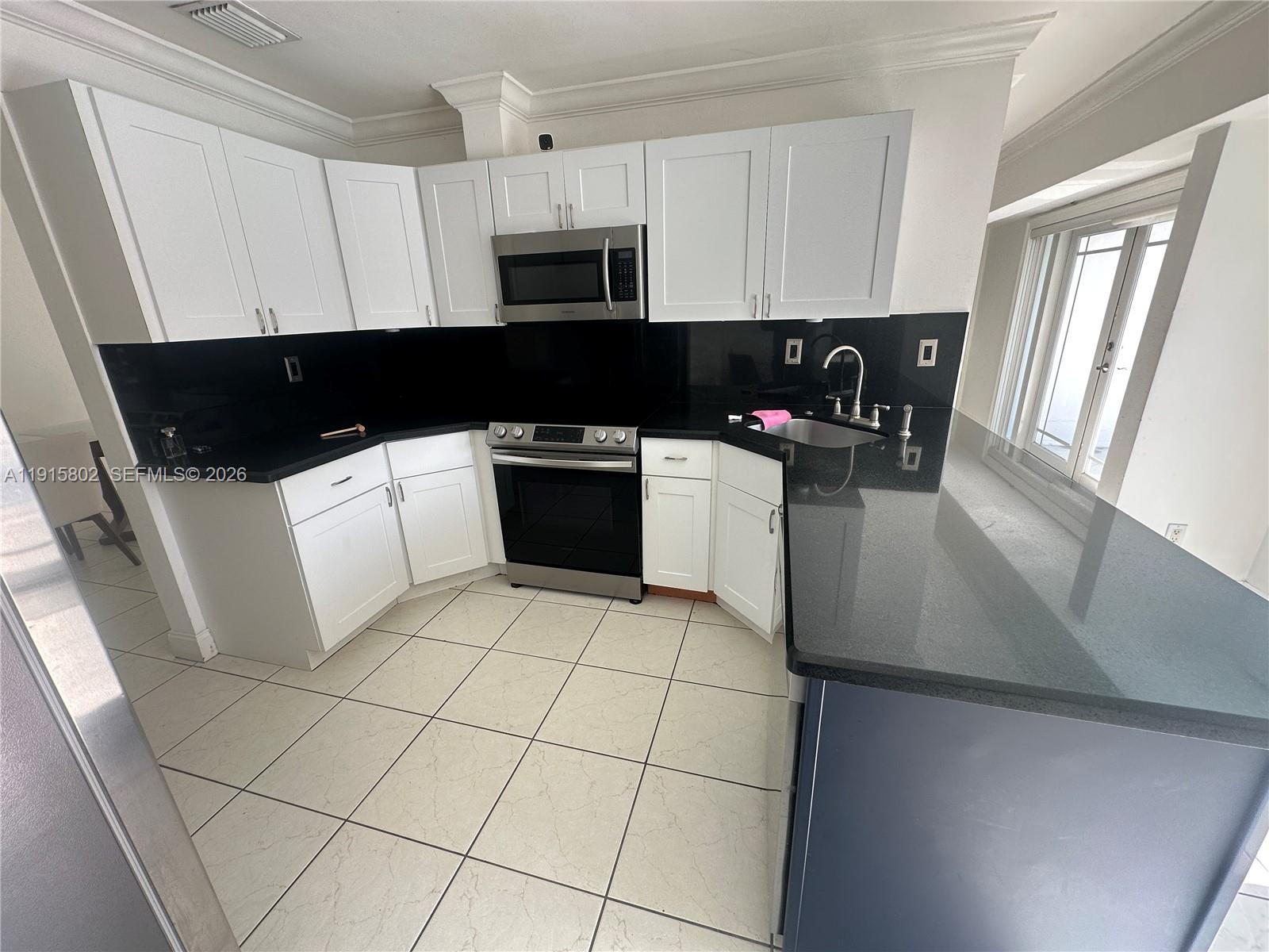 7780 Southwest 28th Street Miami, FL 33155 - Photo 18 of 54 a kitchen with stainless steel appliances a sink a stove a microwave and a refrigerator