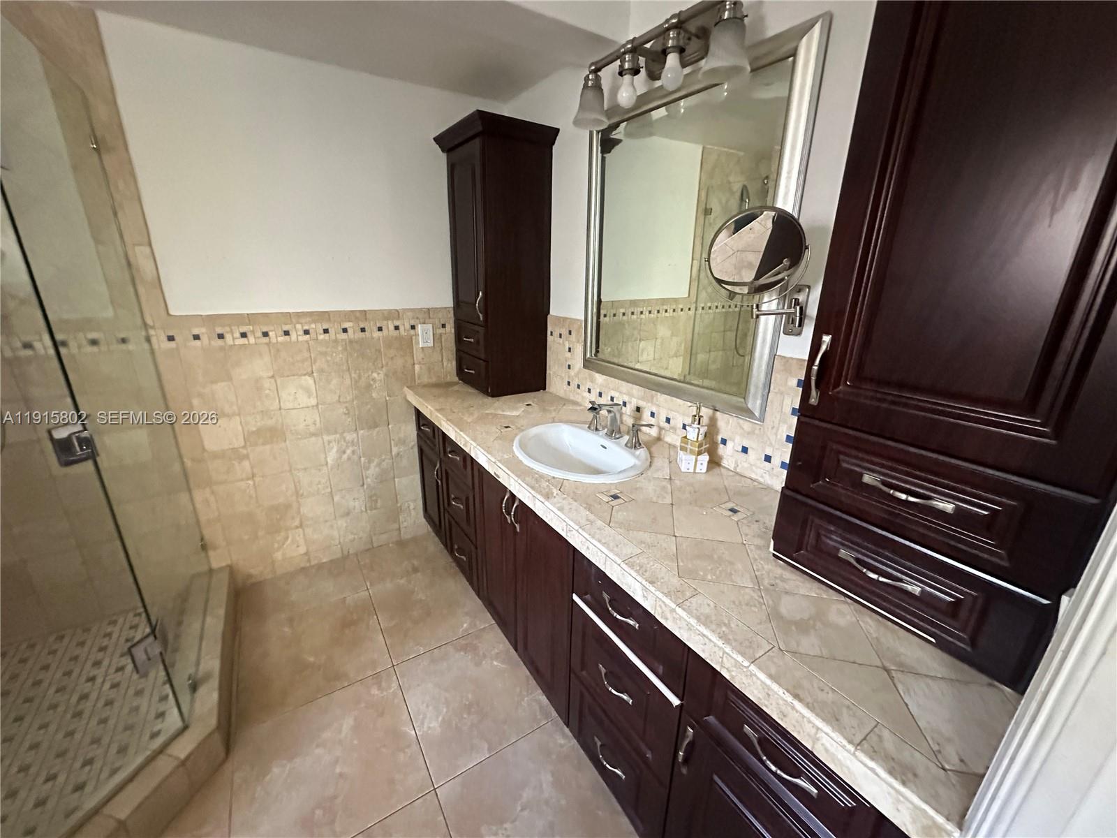 7780 Southwest 28th Street Miami, FL 33155 - Photo 23 of 54 a bathroom with a granite countertop sink a mirror and shower