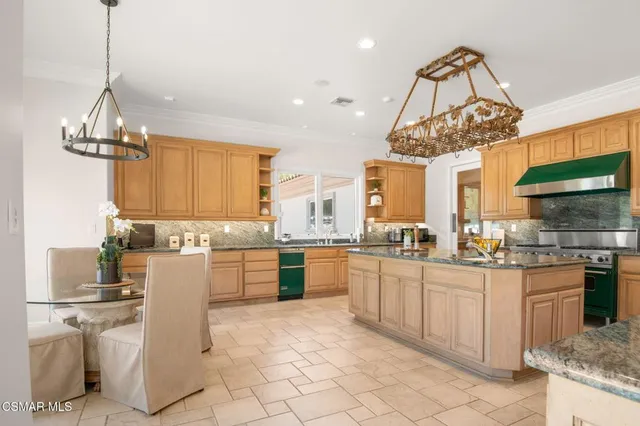 a kitchen with stainless steel appliances granite countertop a refrigerator a sink dishwasher a stove and white cabinets with wooden floor