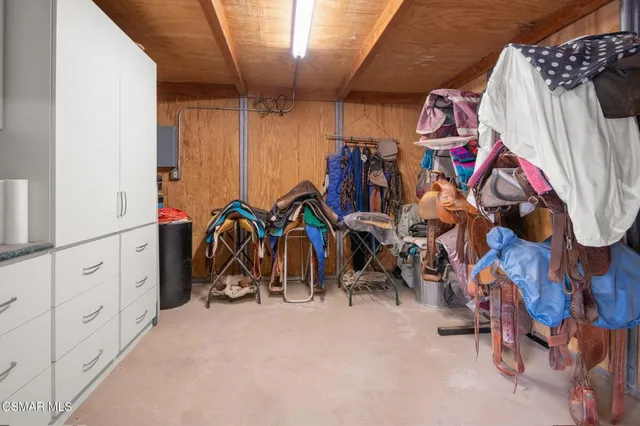 a view of a white house in front of a big yard with plants and large trees
