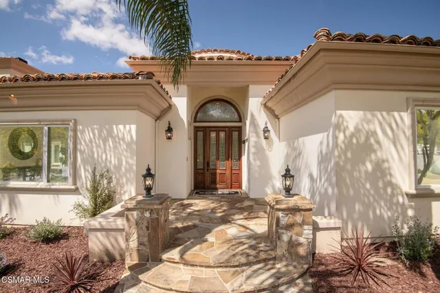 a living room with furniture large mirror and a potted plant