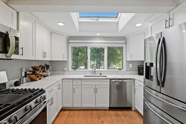 a view of an empty room with window and hardwood floor