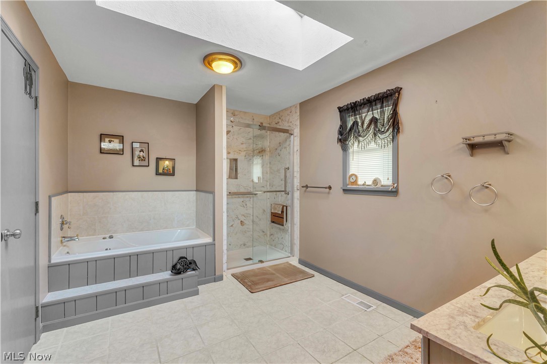 563 North Carpenter Road Brunswick, OH 44212 - Photo 19 of 45 Full bathroom with a skylight, a garden tub, a marble finish shower, vanity, and light tile patterned floors