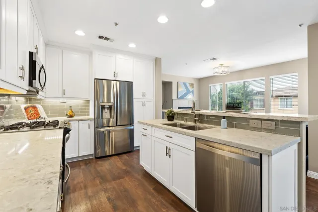 a living room with stainless steel appliances granite countertop a sink and a large window