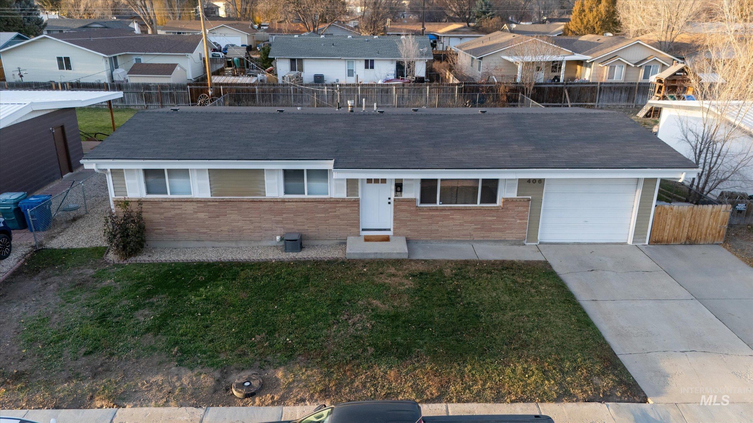 406 Chestnut Street Mountain Home, ID 83647 - Photo 22 of 31 Ranch-style home with brick siding, driveway, an attached garage, and a residential view