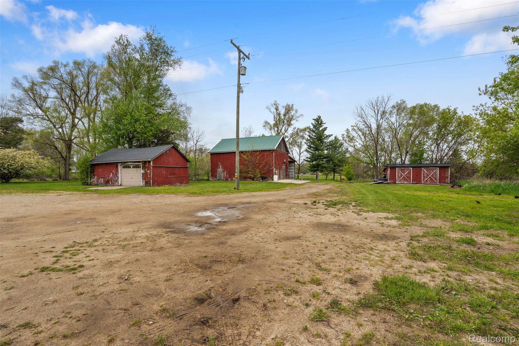 1775 Imlay City Road Lapeer, MI 48446 - Photo 39 of 60 View of green lawn featuring an outdoor structure, a barn, a detached garage, and dirt driveway