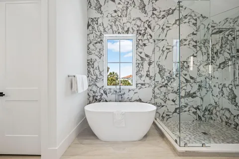a white bath tub sitting in a bathroom next to a window