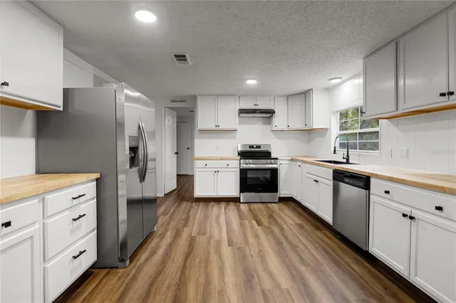 a kitchen with white cabinets stainless steel appliances and sink
